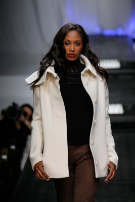 Model struts down runway in white jacket