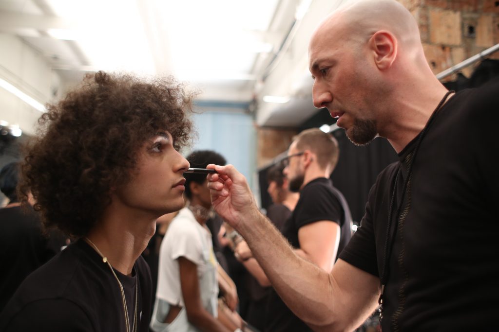 MAC Pro Makeup Artist Victor Cembellin touching up a models foundation backstage. Photo by: Tori Repp