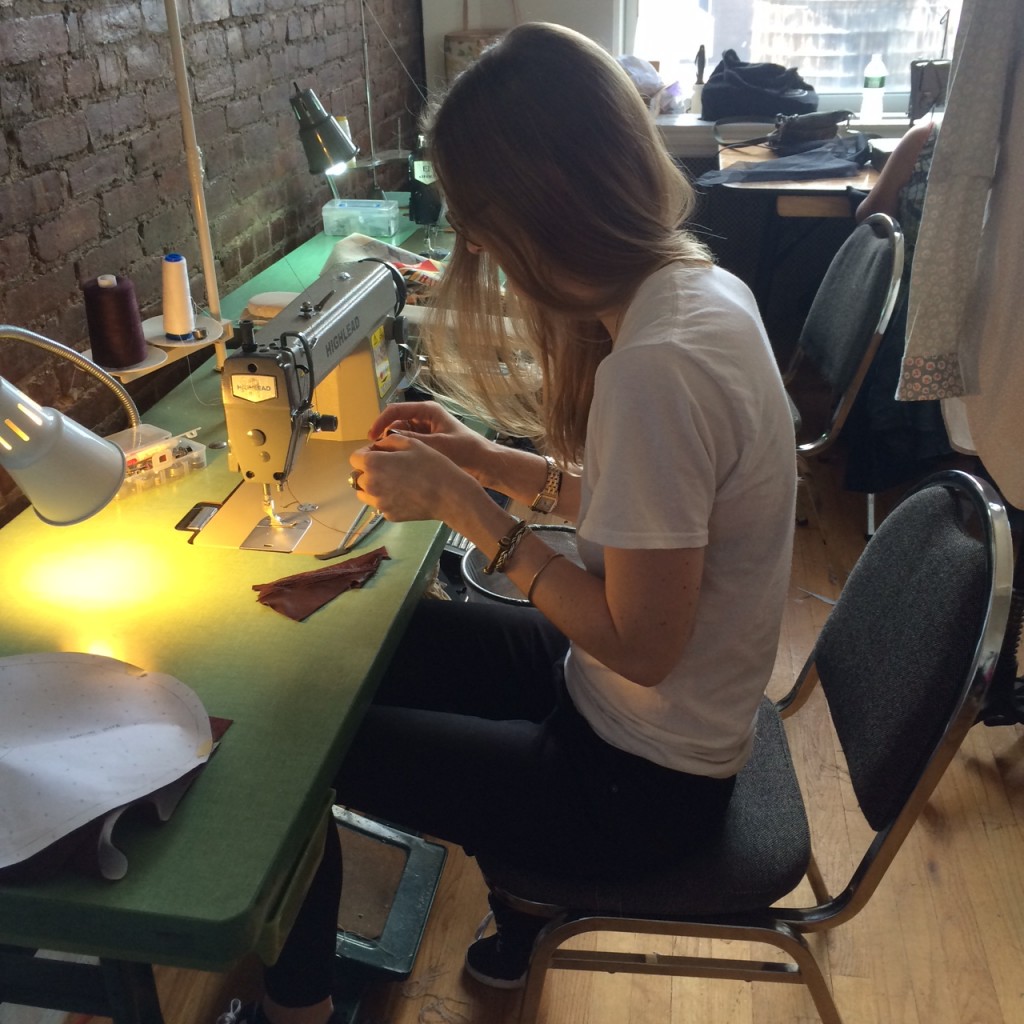 Madison Detro, MFA Fashion Design, at a sewing machine in the workroom